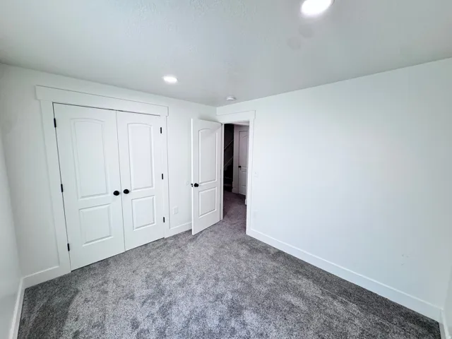 Room featuring white walls, gray textured carpeting, and recessed lighting