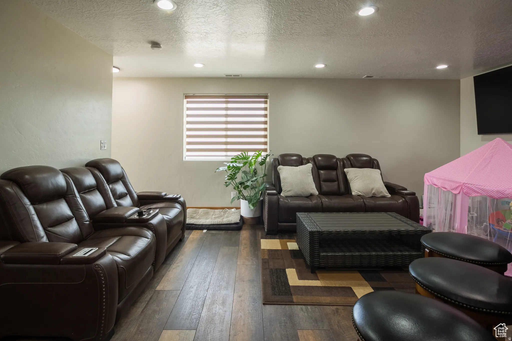 Spacious interior room featuring wood-finish flooring, recessed lighting, and a window with horizontal blinds