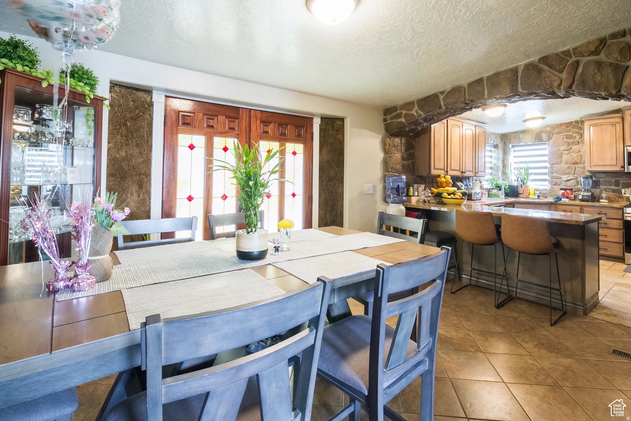 Dining area featuring a wood-finish table, tile flooring, and a stone archway