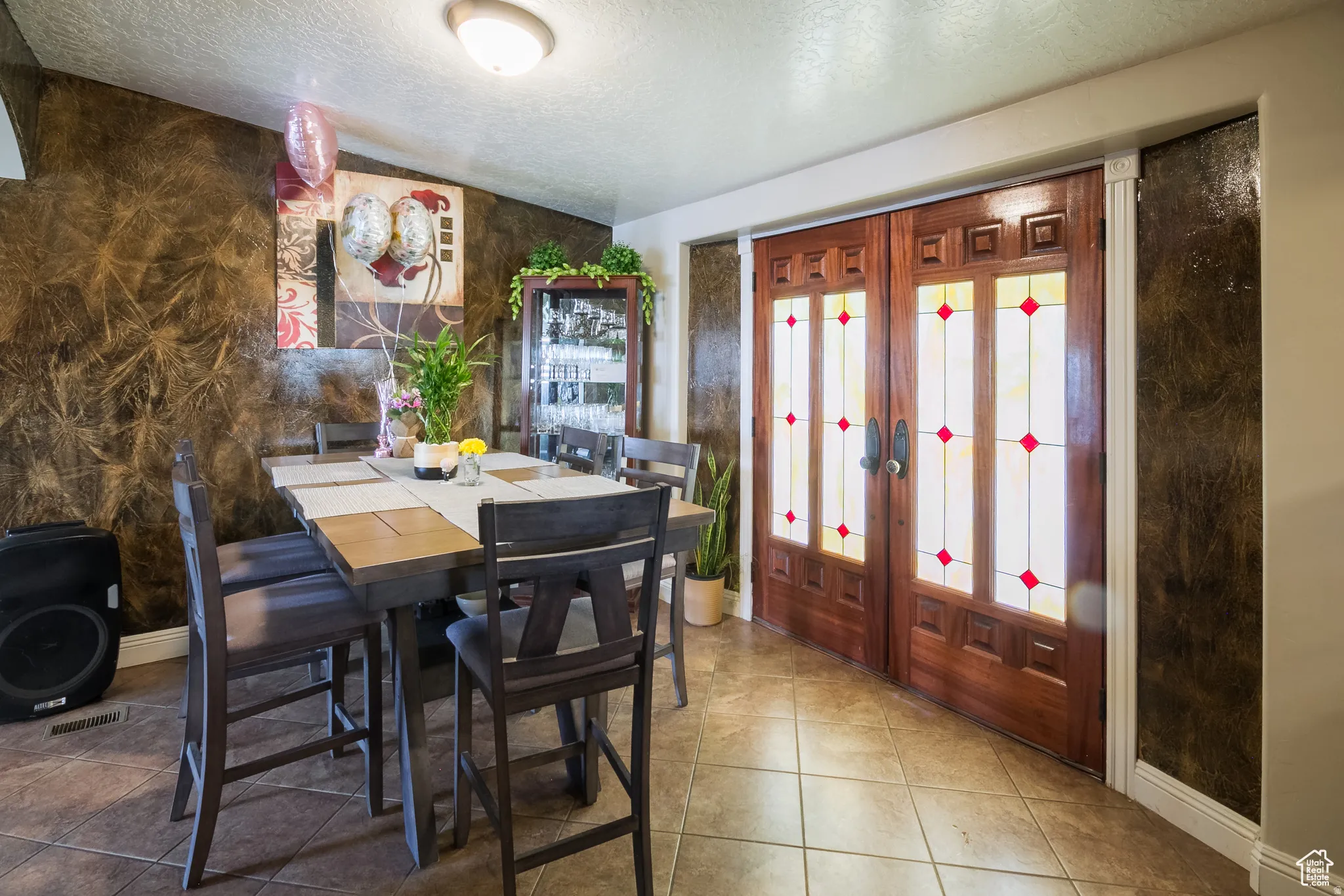 Entryway featuring ornate double doors with stained glass accents, set against textured wall finishes
