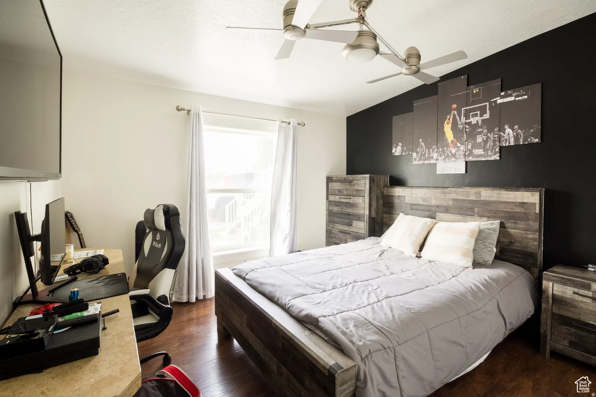 Interior room featuring a wood-finish bed frame with matching headboard and nightstand, accented by a dark feature wall
