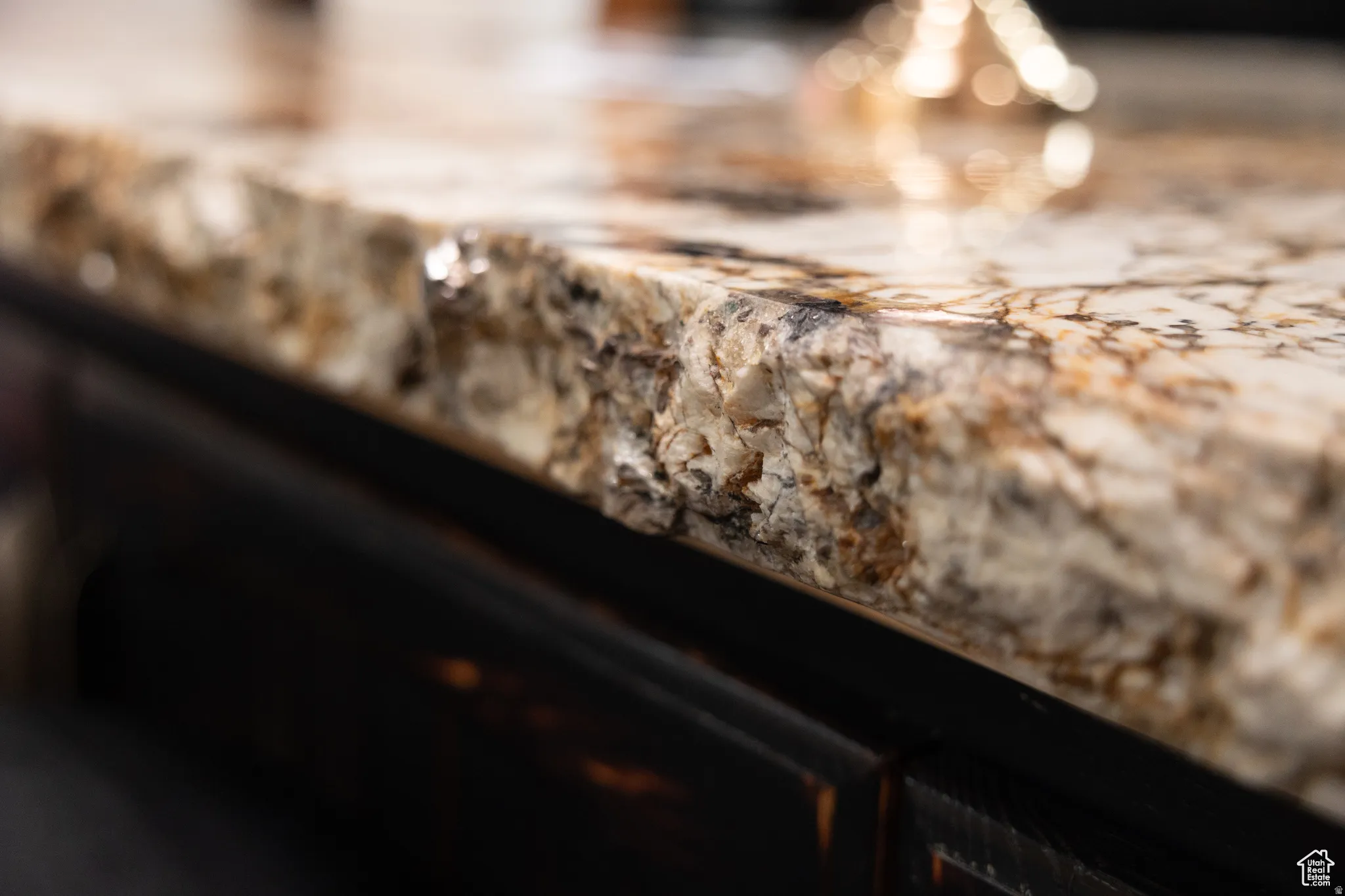Polished natural stone countertop with a variegated pattern of cream, brown, and black tones