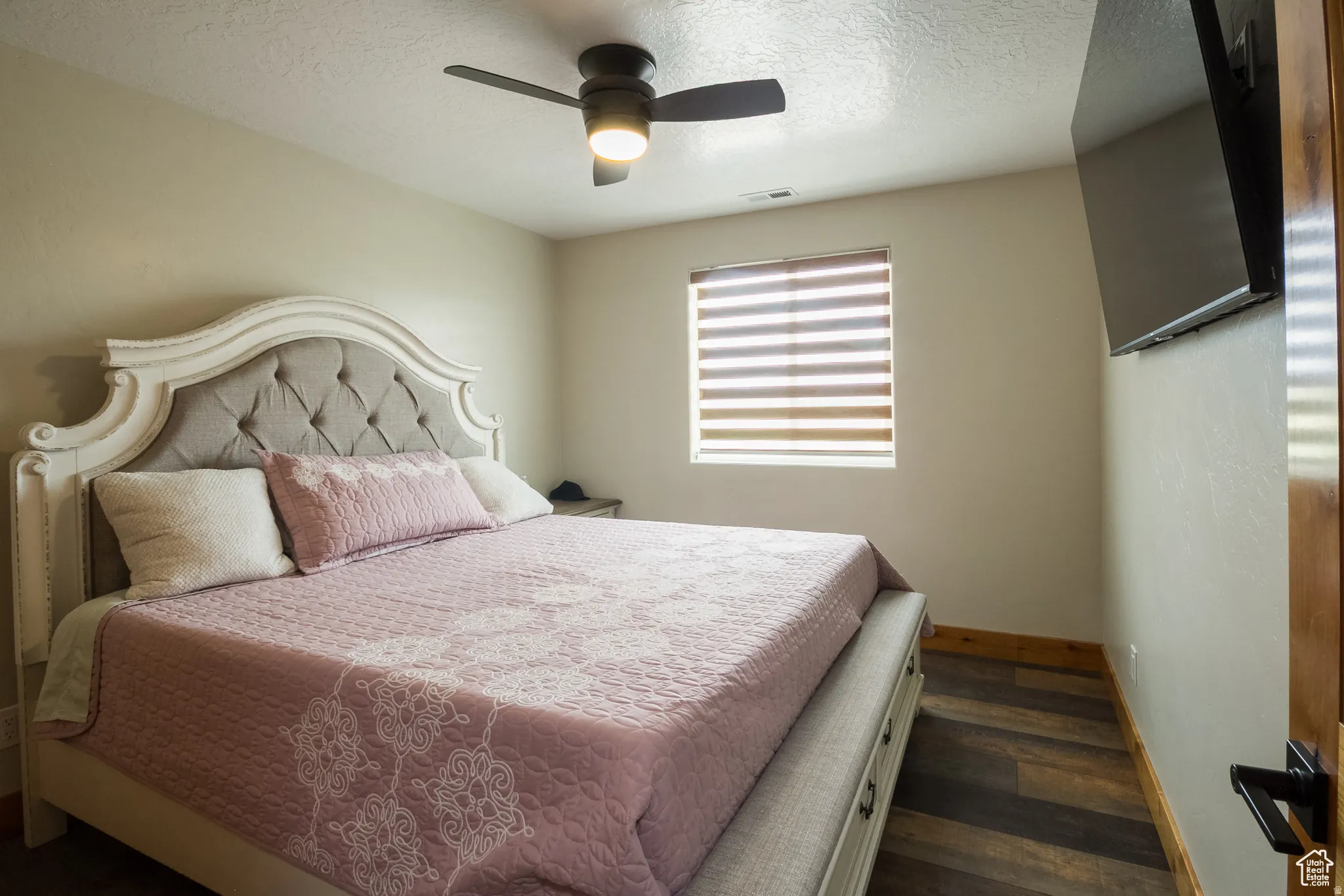 Bedroom featuring wood-finish flooring, a contemporary ceiling fan with integrated lighting, and a window with horizontal blinds