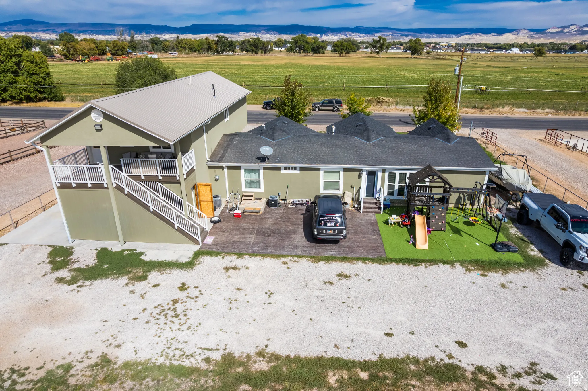 Single-story residence with a two-story addition featuring a balcony, complemented by a large gravel area and an artificial turf patio
