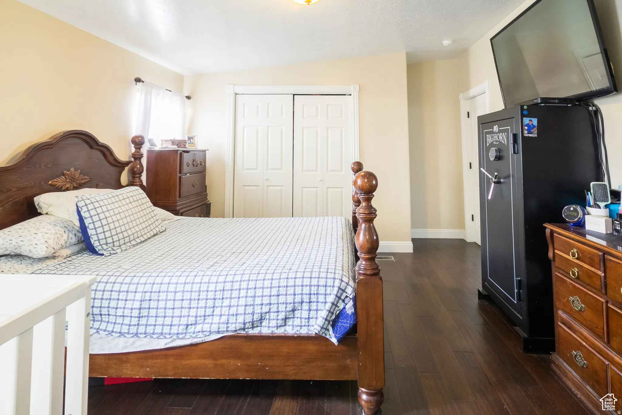 Bedroom featuring dark wood-finish flooring, light-toned walls, and a closet with bi-fold doors