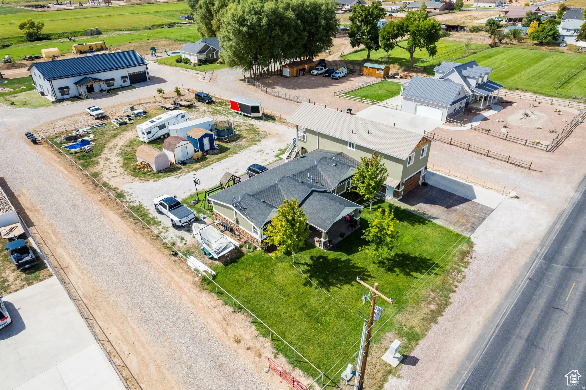 Expansive property featuring a two-story residence with a detached garage, a large separate outbuilding, gravel driveways, and a grassy front yard