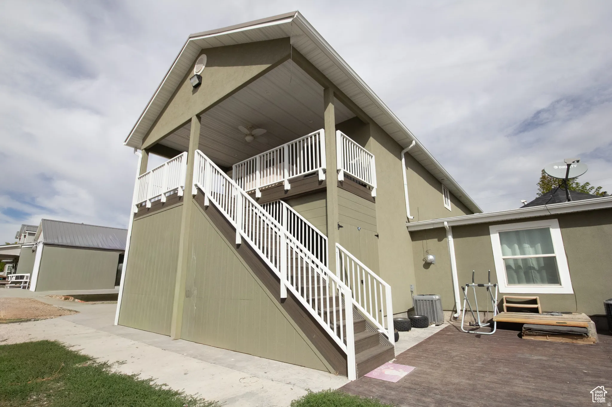 Exterior featuring a covered upper-level deck with white railings and an outdoor ceiling fan