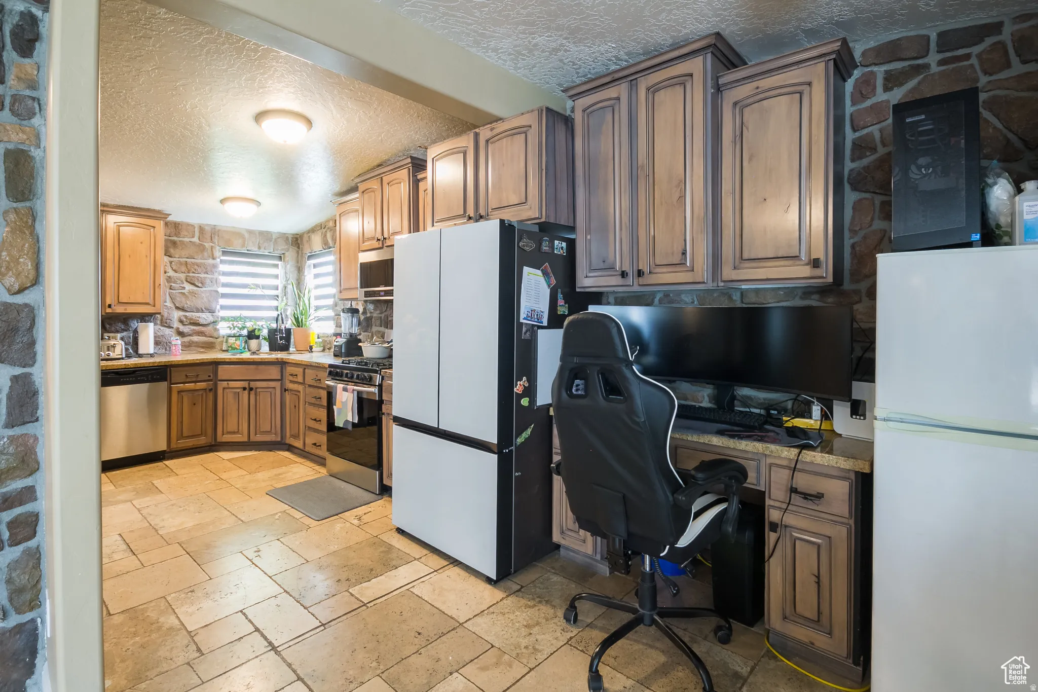 Kitchen featuring stone-finish walls, tile flooring, and light wood cabinetry