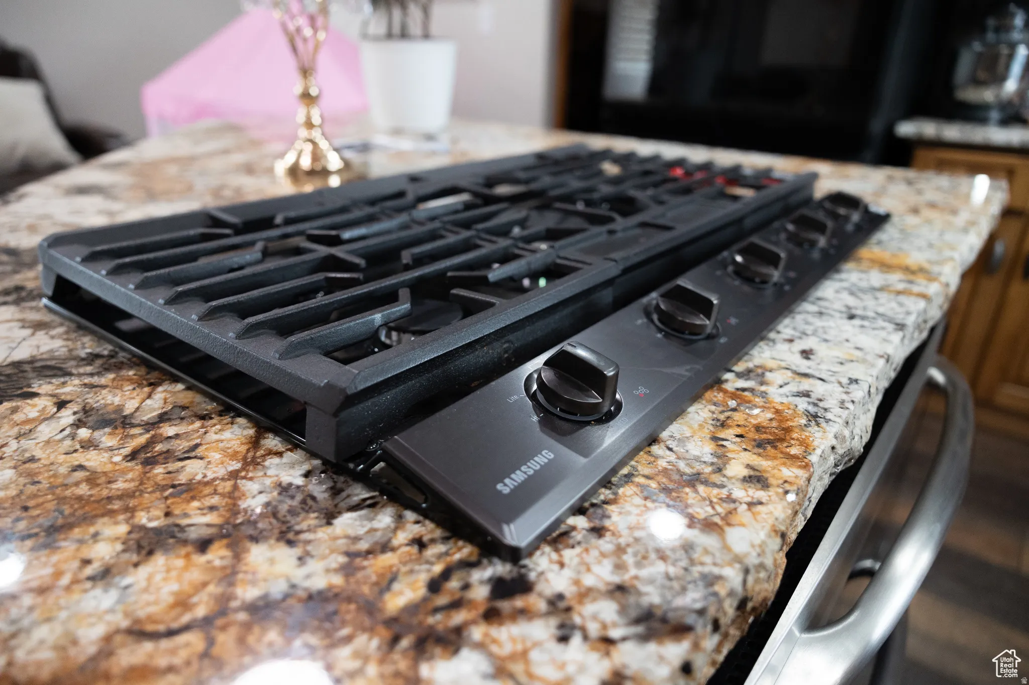 Integrated black gas cooktop with five burners set into a polished natural stone countertop