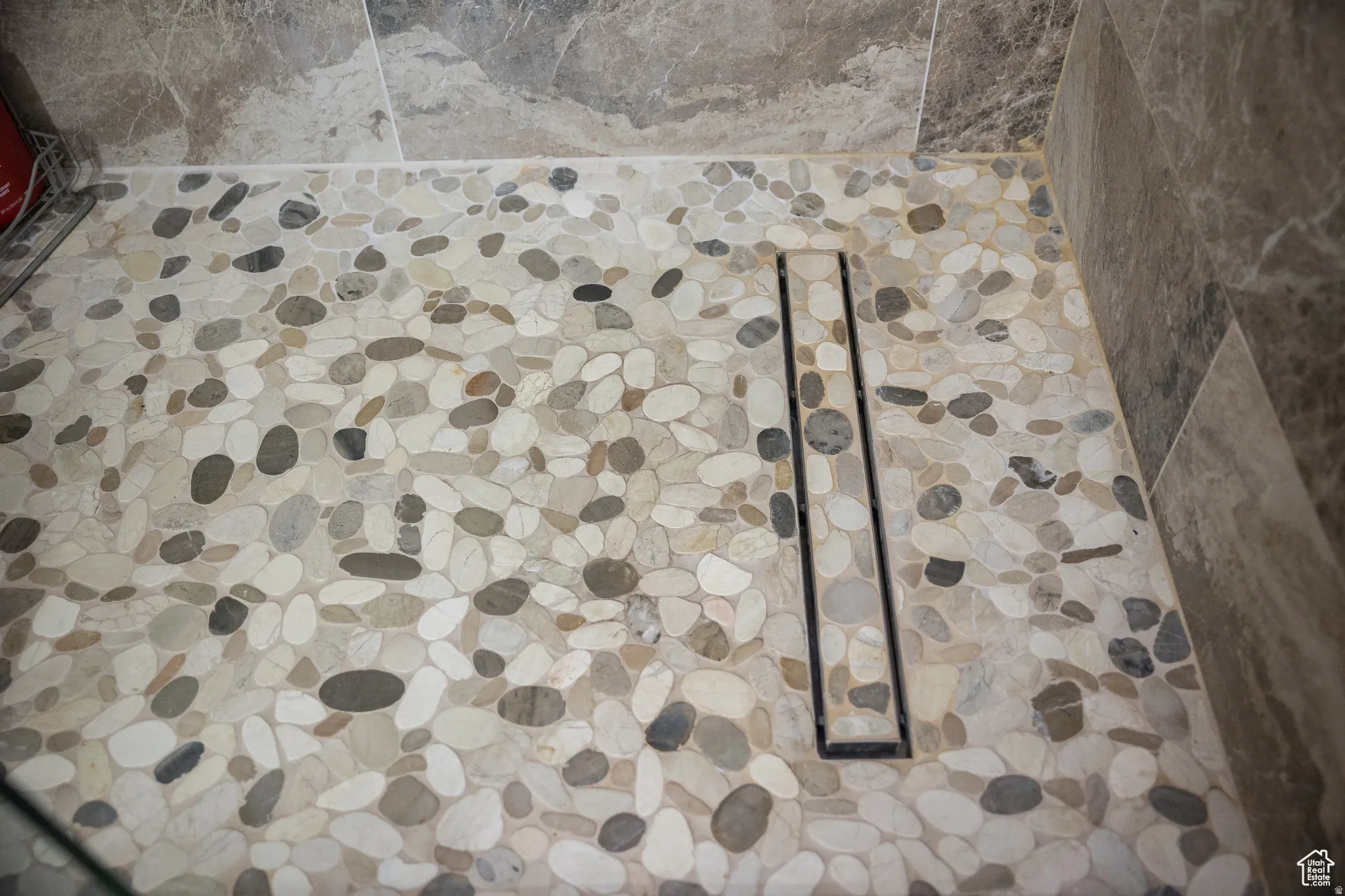 Shower floor featuring pebble tile and a linear drain