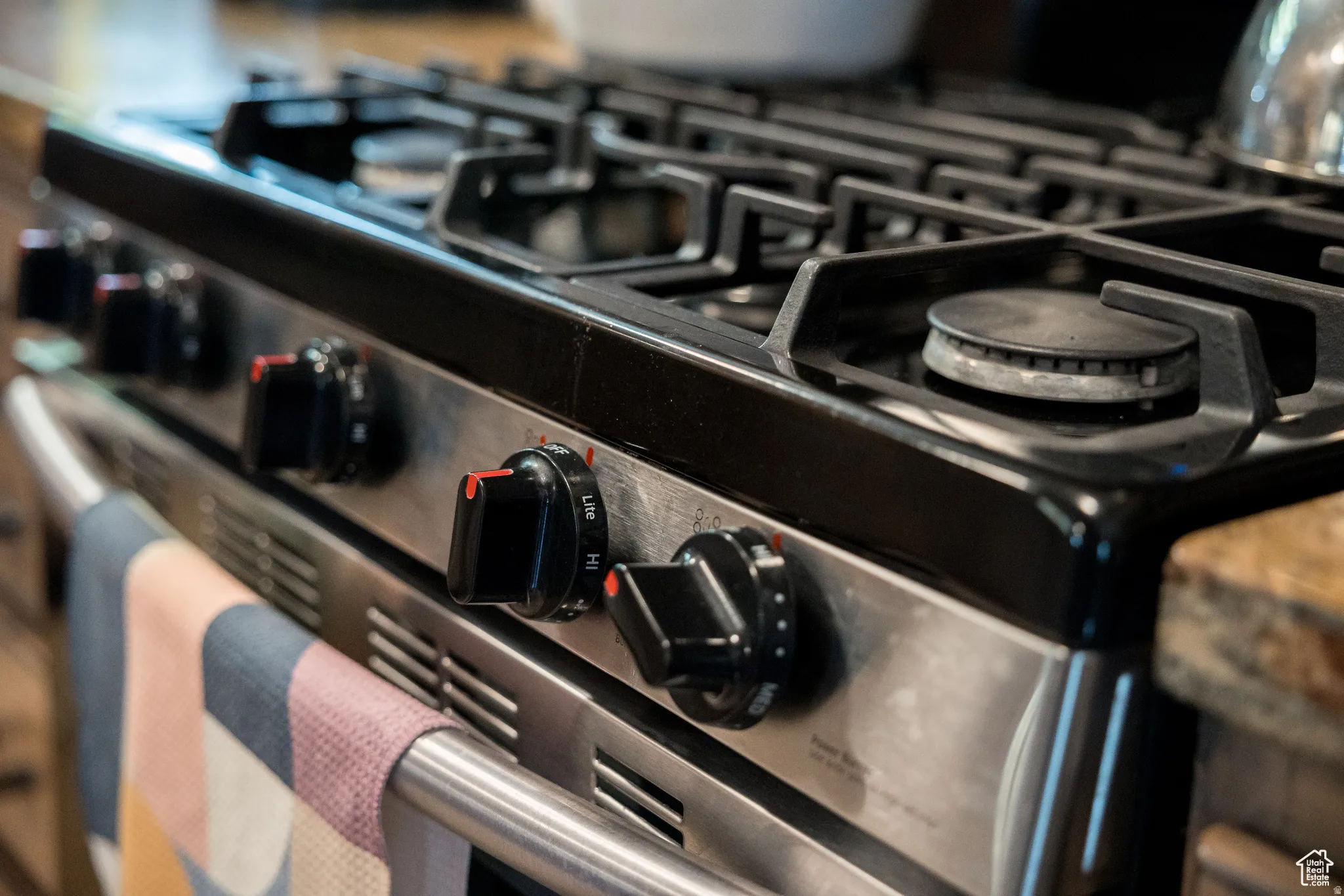 Stainless steel range featuring a black cooktop, five gas burners, and front-mounted control knobs