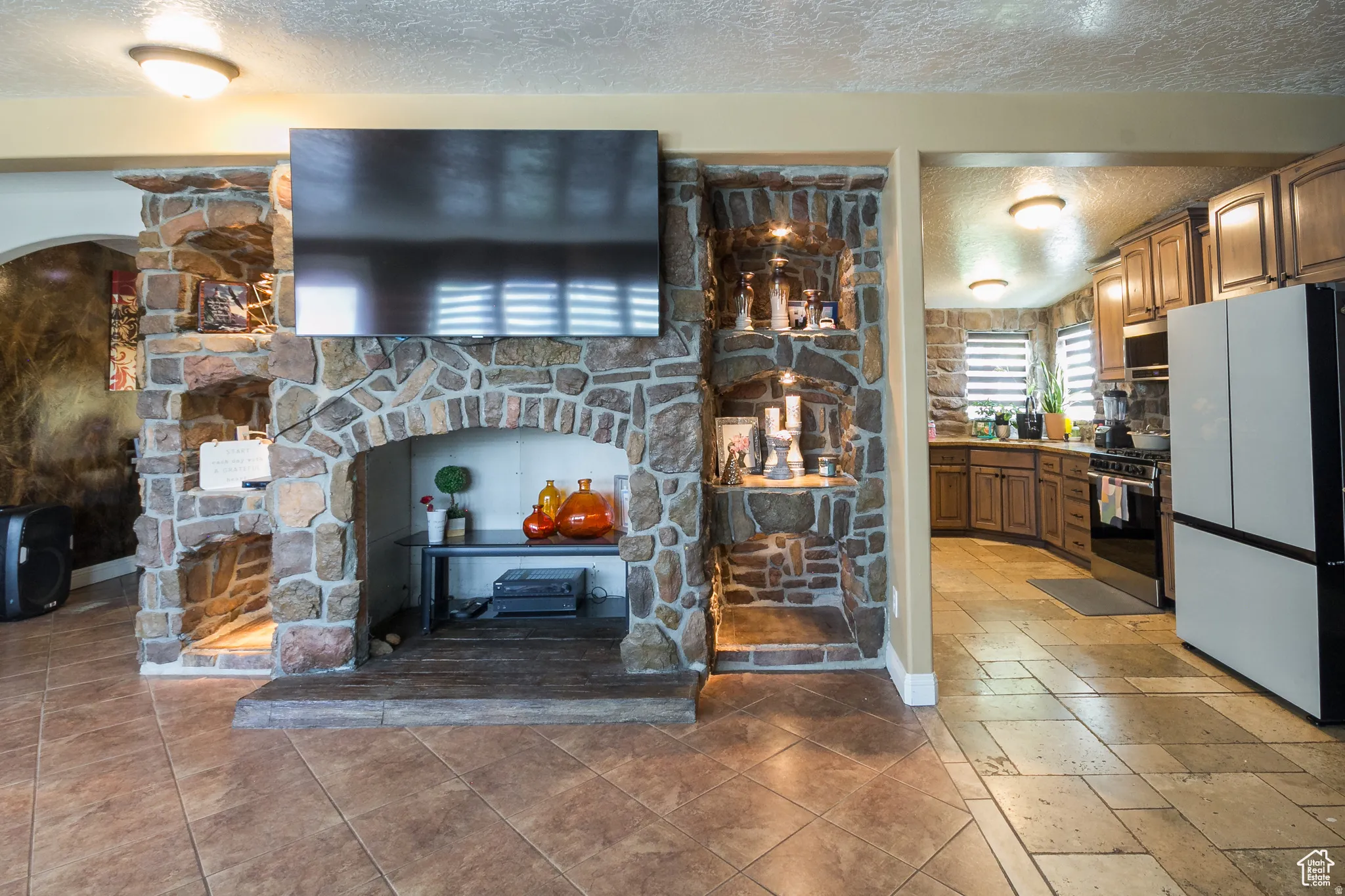 Expansive stone fireplace with built-in shelving, complemented by large format tile flooring
