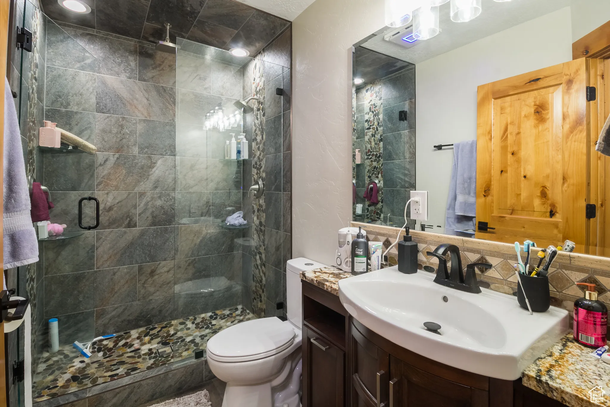 Bathroom featuring a tiled shower with a pebble floor, glass enclosure, and recessed lighting