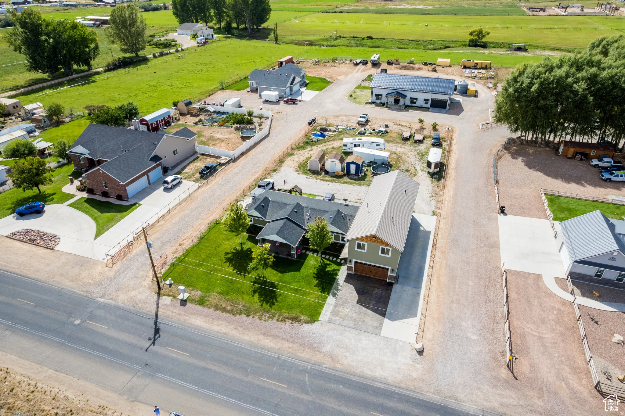 Rural property featuring multiple structures, paved driveways, green lawns, and extensive gravel areas