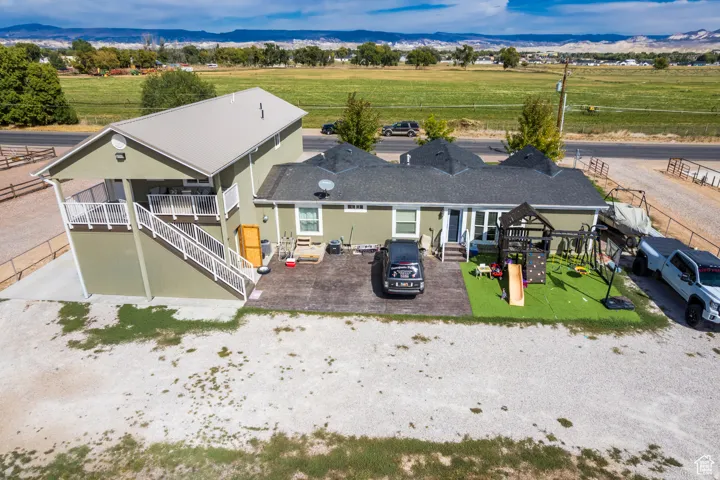 Single-story residence with a two-story addition featuring a balcony, complemented by a large gravel area and an artificial turf patio