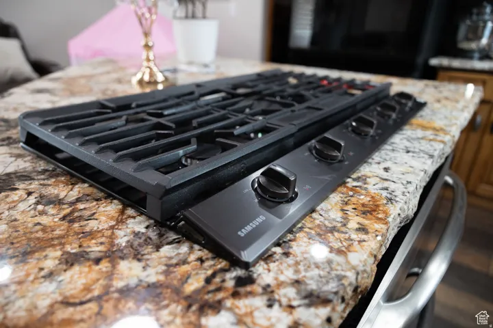 Integrated black gas cooktop with five burners set into a polished natural stone countertop