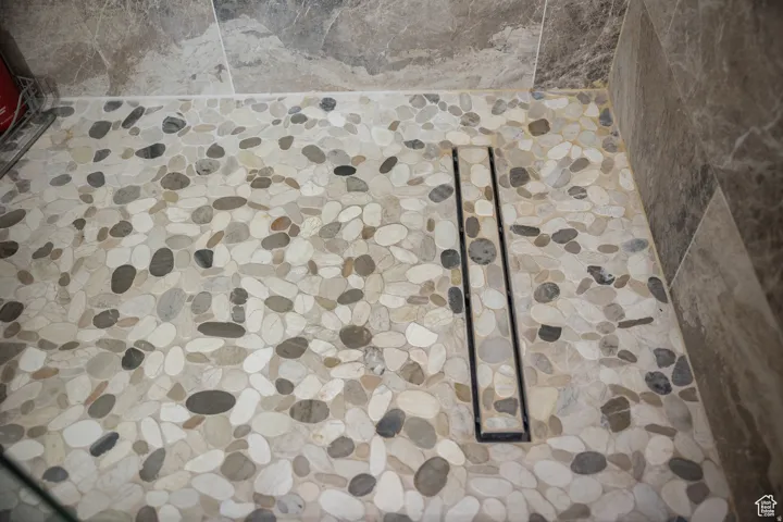 Shower floor featuring pebble tile and a linear drain