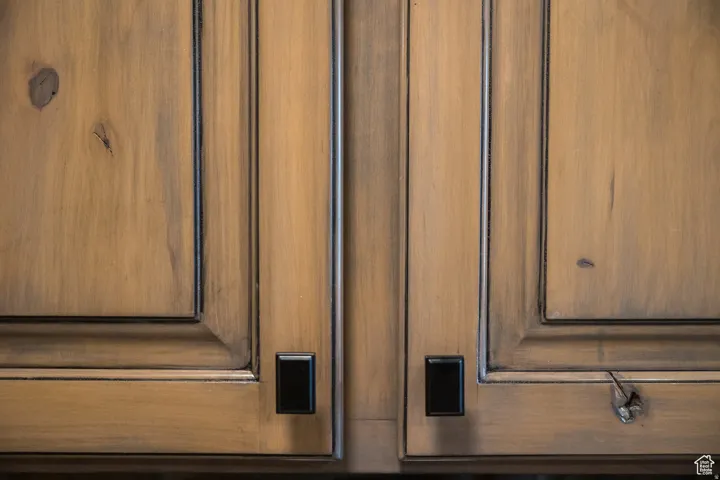Wooden cabinetry featuring a distressed finish, raised panel doors, and black rectangular hardware