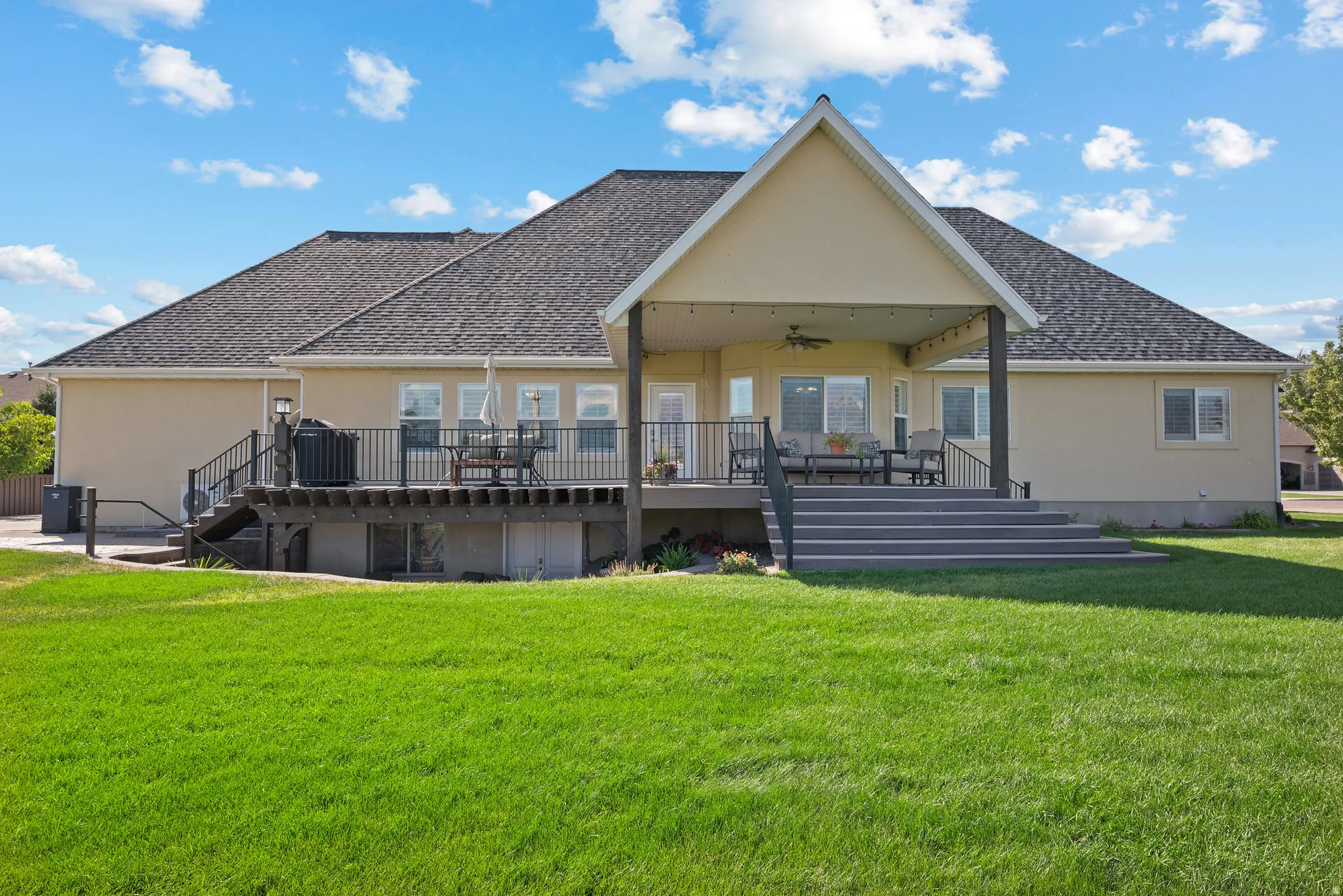 Rear exterior featuring a large covered patio with string lighting and a ceiling fan