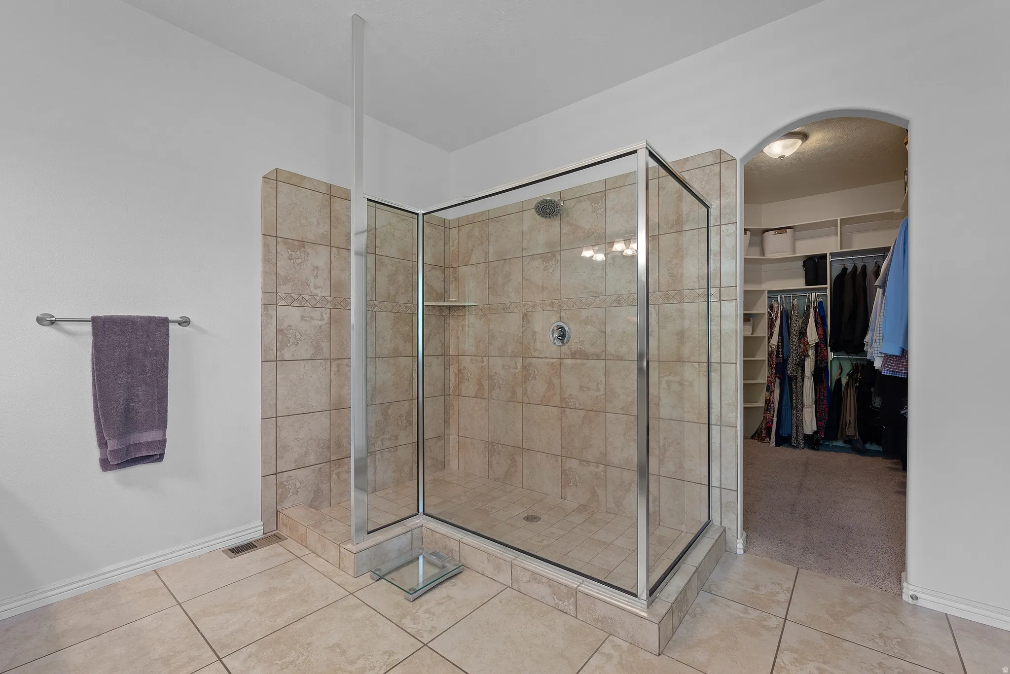 Glass-enclosed shower with subway tile surround and integrated shelving