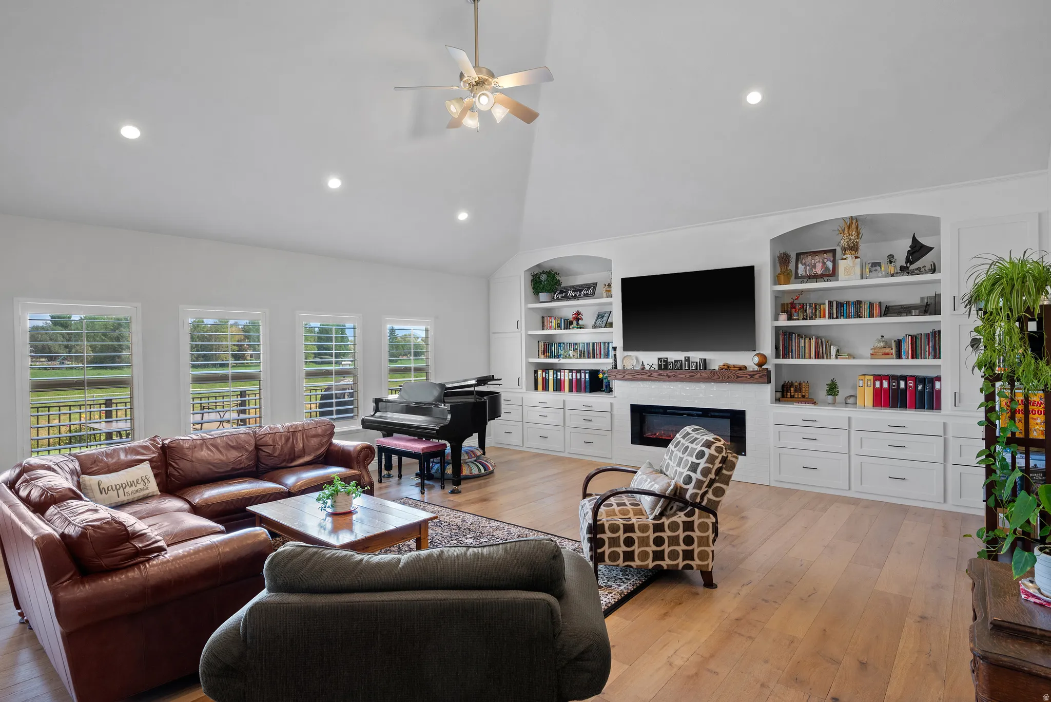 Spacious living area featuring high vaulted ceilings, light wood-finish flooring, and multiple windows
