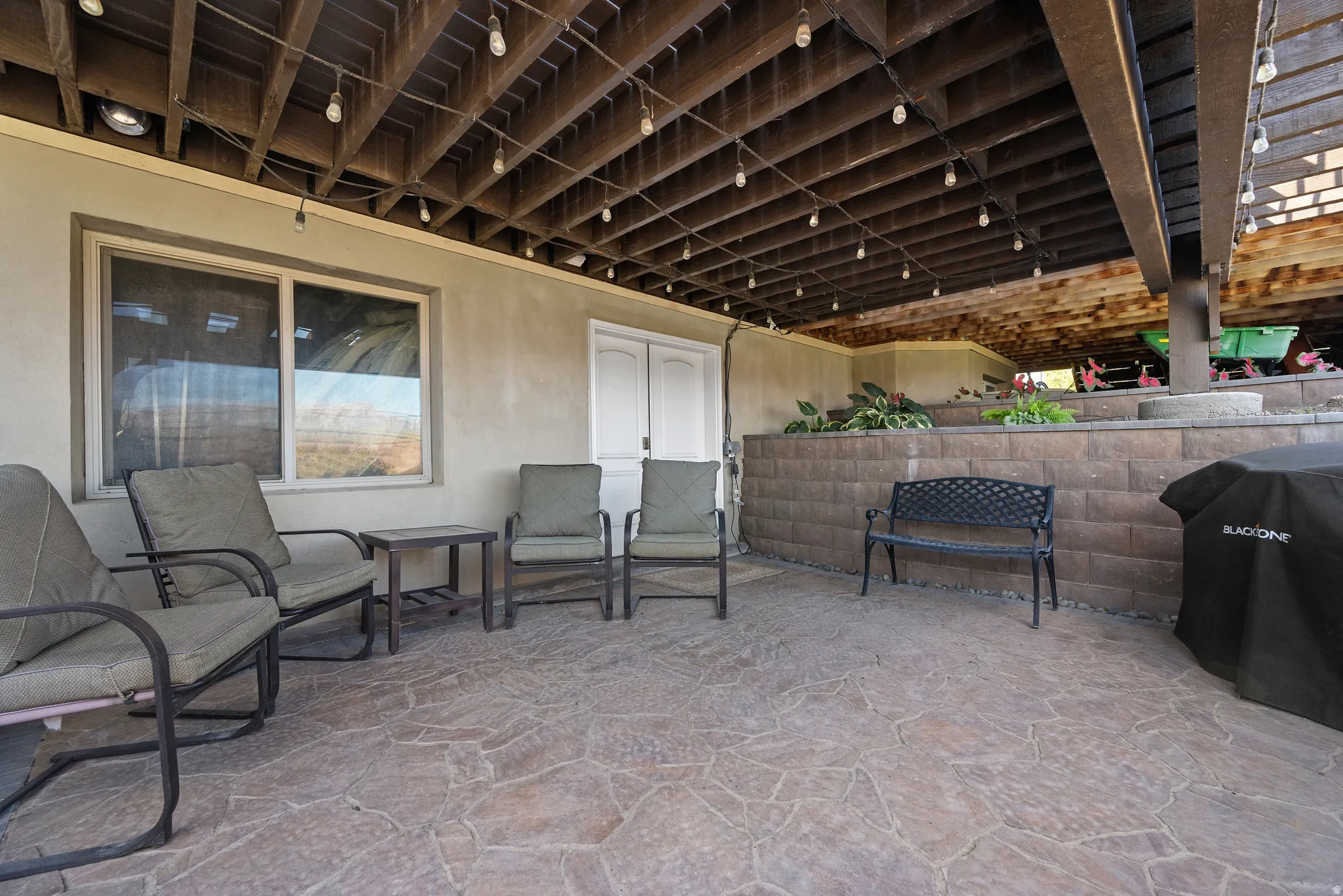 Paved patio area featuring an exposed beam ceiling with string lighting and recessed fixtures