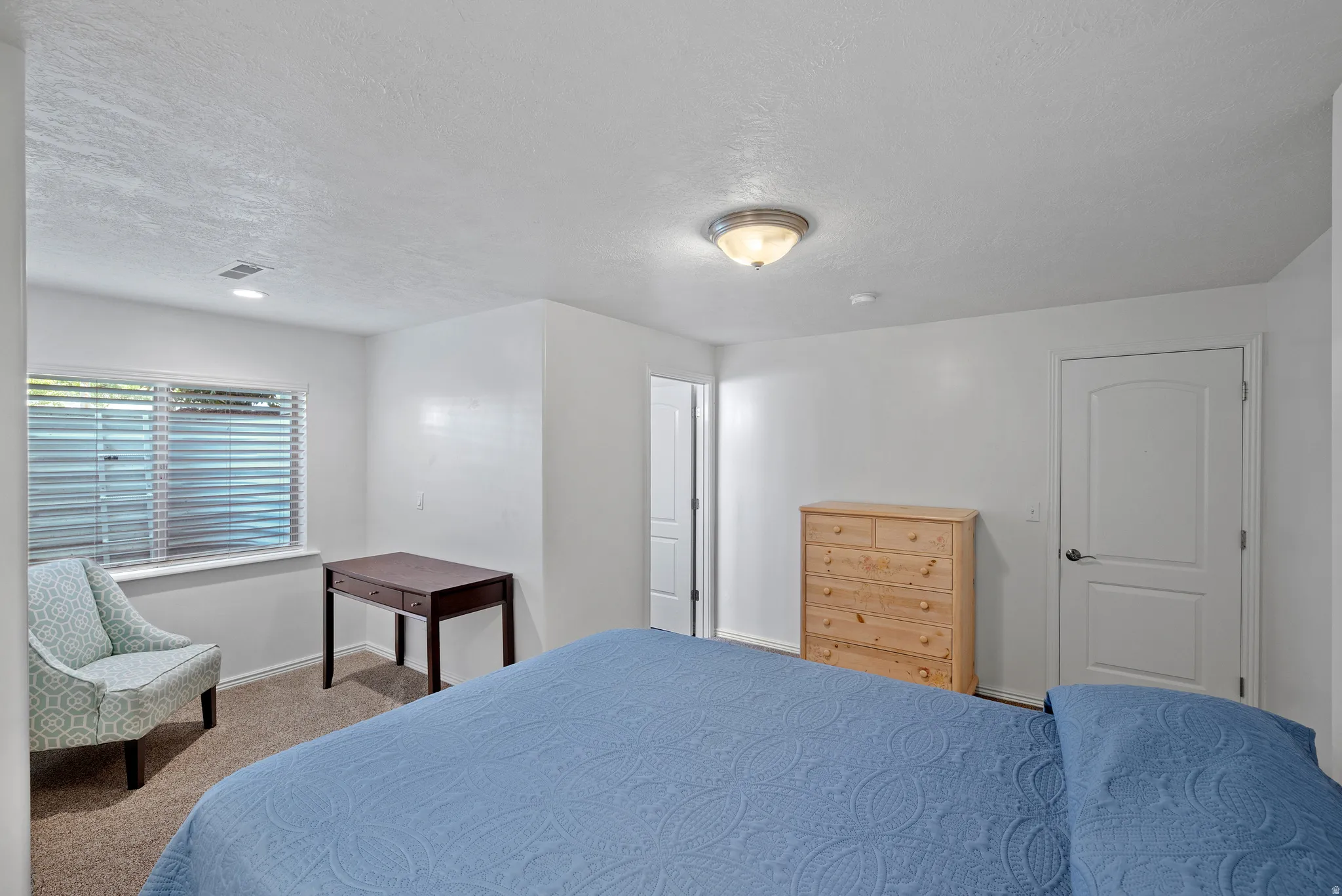 Carpeted room featuring white walls and a window with horizontal blinds