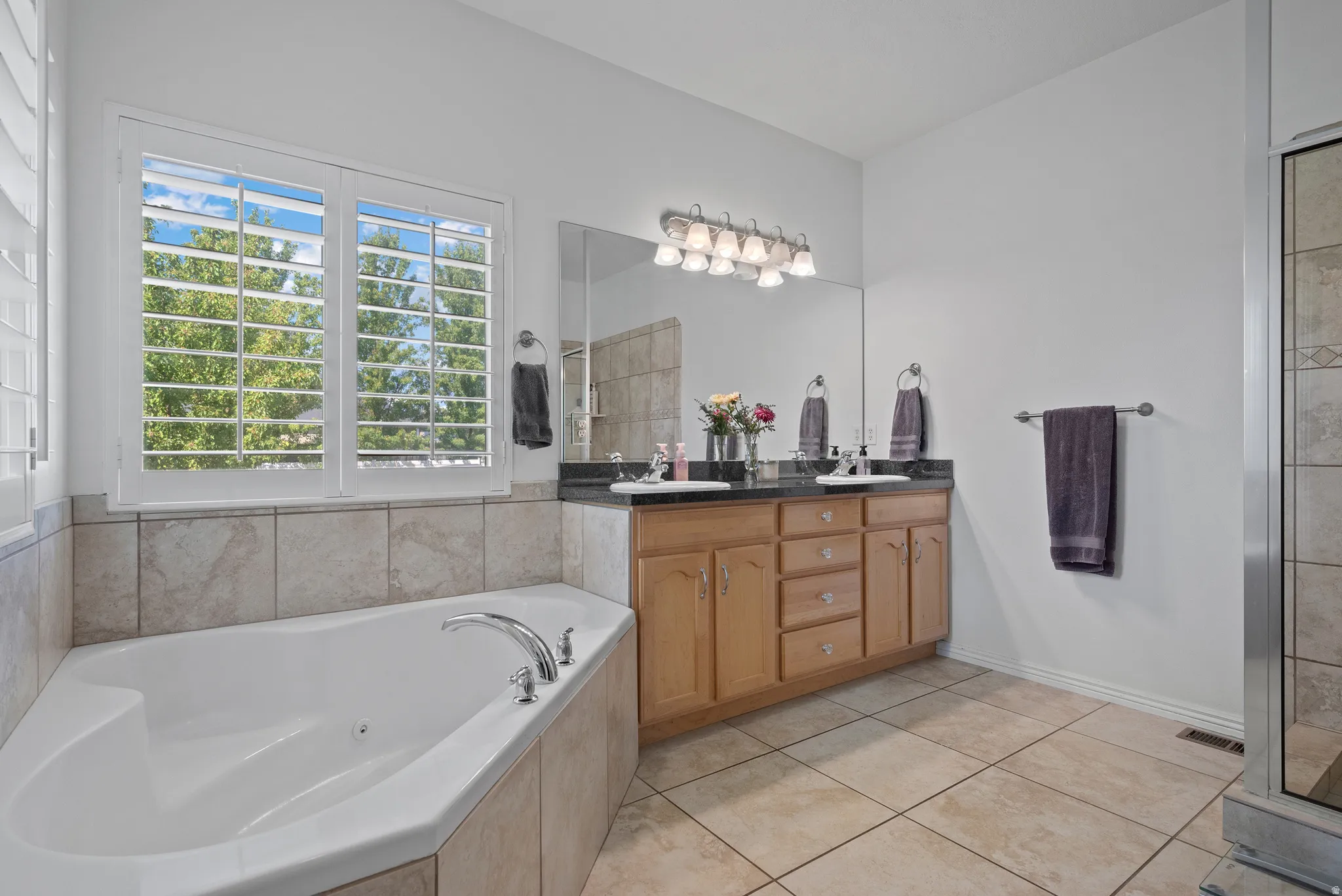 Deep soaking tub with tile surround and white plantation shutters