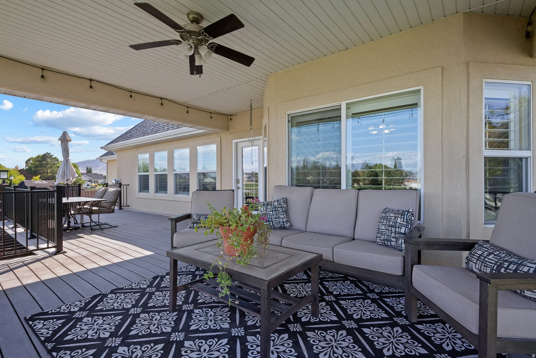 Covered outdoor deck featuring composite decking, a ceiling fan, recessed lighting, and multiple windows