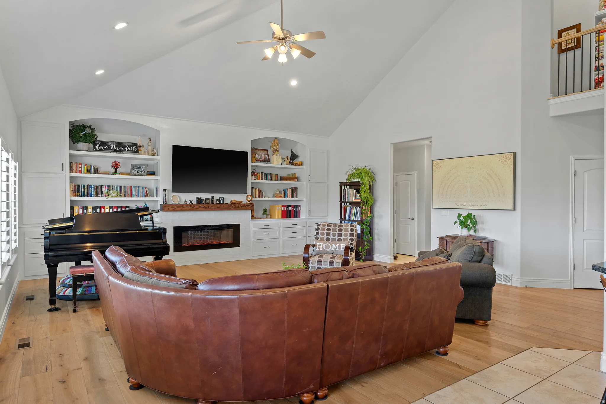 Spacious living area featuring a vaulted ceiling with a ceiling fan, recessed lighting, and wood-finish flooring