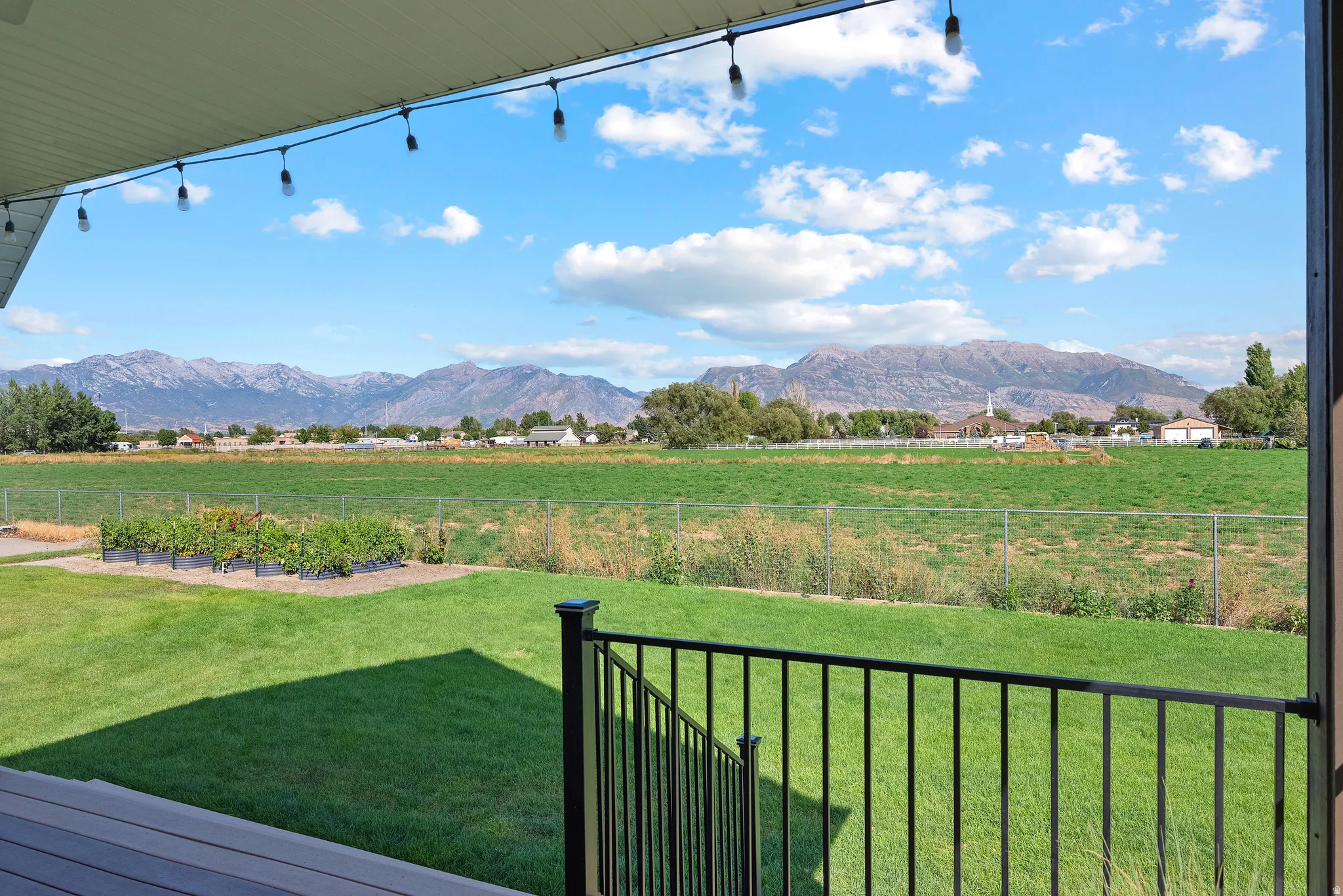 Expansive backyard featuring a manicured lawn, raised garden beds, and a chain-link fence
