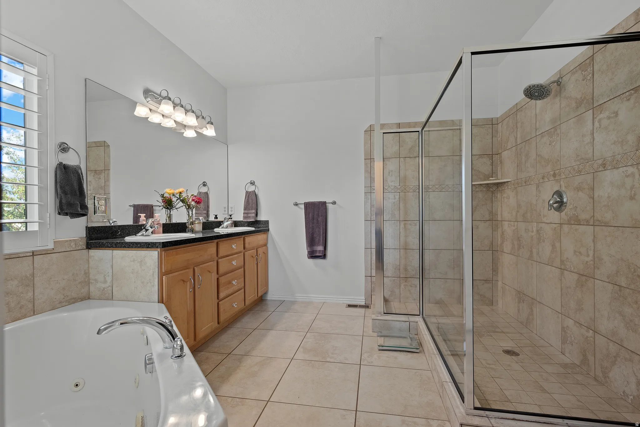 Spacious bathroom featuring a large glass-enclosed shower with tiled walls and a built-in shelf