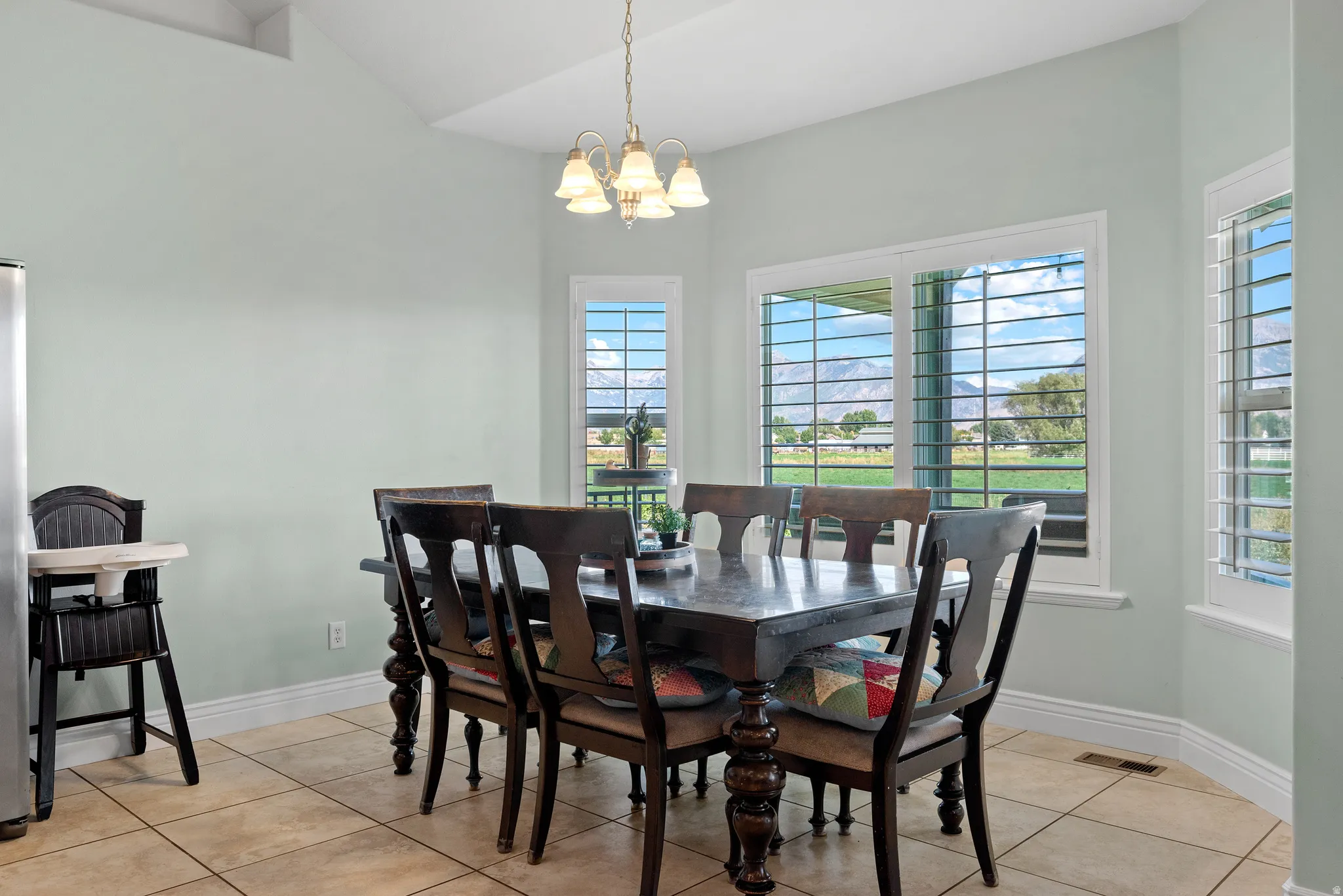 Dining area featuring ample natural light, vaulted ceilings, and tile flooring