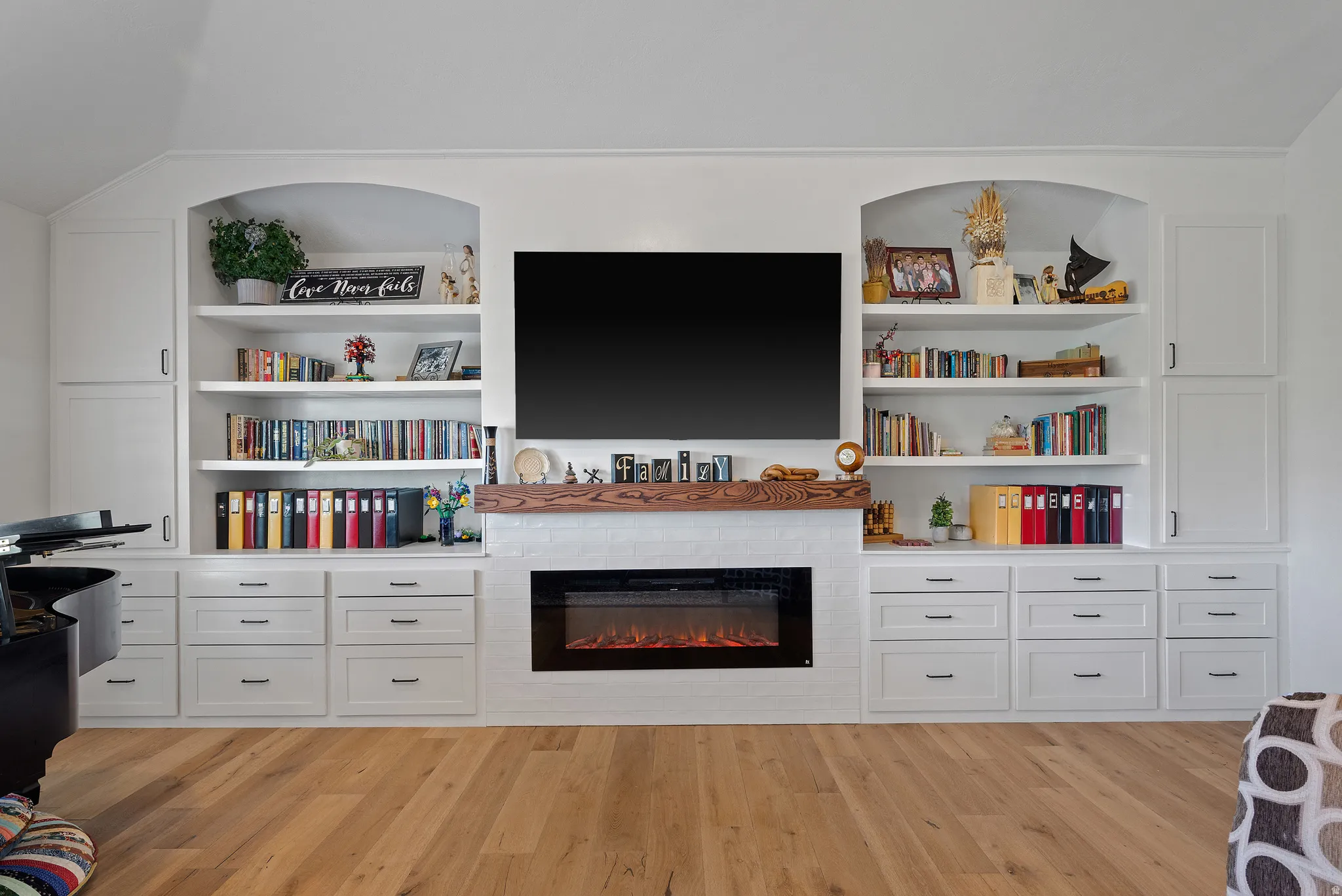 Built-in entertainment center featuring a modern electric fireplace with white tile surround, a wood-finish mantel, and integrated media storage