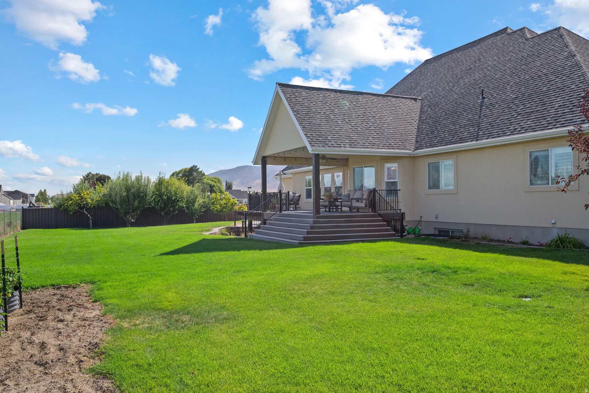Expansive green lawn with a tiered composite deck featuring a covered patio area