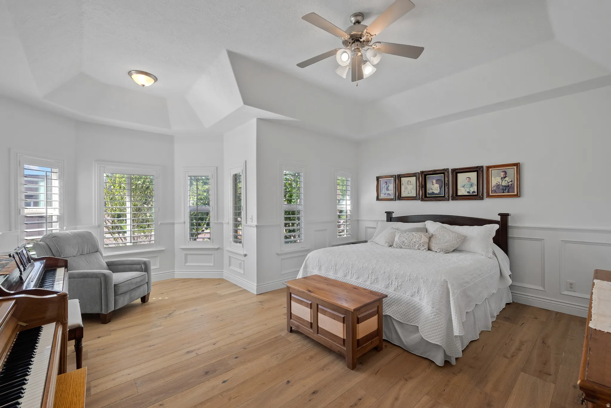 Spacious room featuring light wood-finish flooring, white paneling, and a tray ceiling