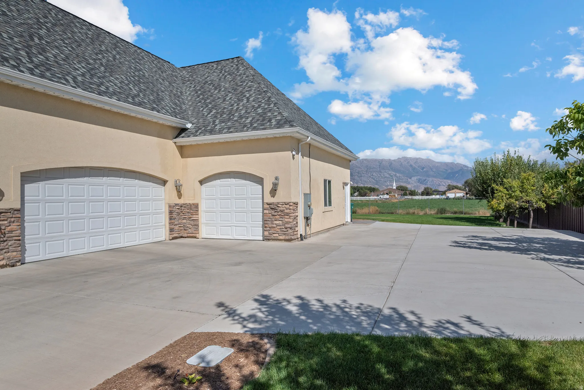 Two-car garage with arched entryways, stacked stone accents, and carriage-style overhead doors