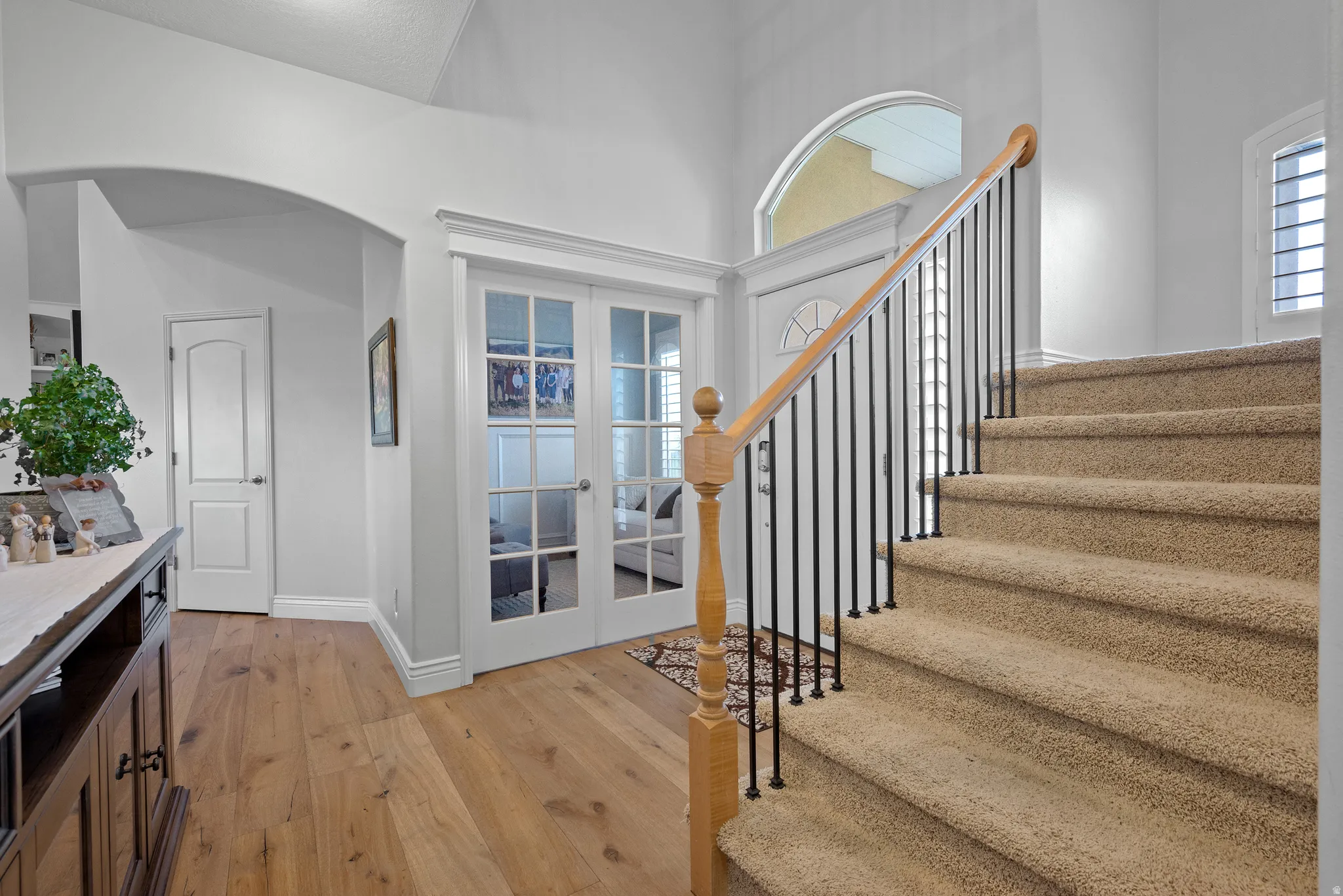 Entryway featuring a carpeted staircase with a wood handrail and black metal spindles