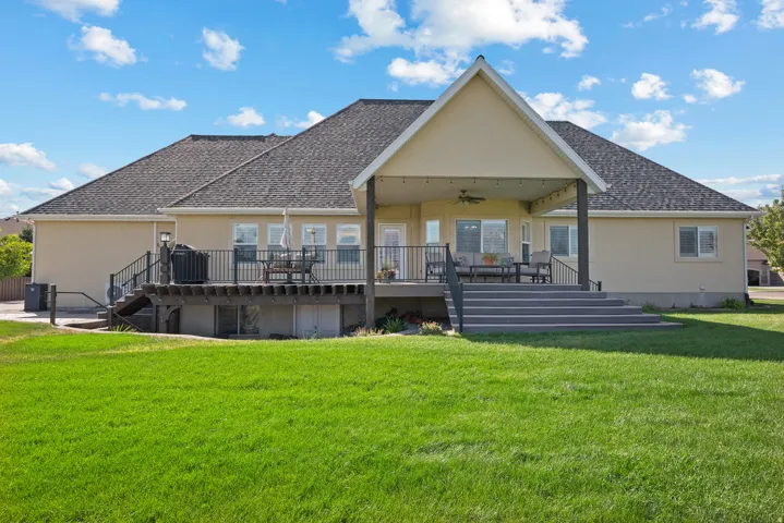 Rear exterior featuring a large covered patio with string lighting and a ceiling fan