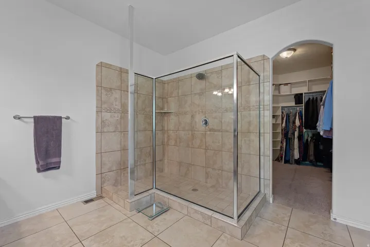 Glass-enclosed shower with subway tile surround and integrated shelving