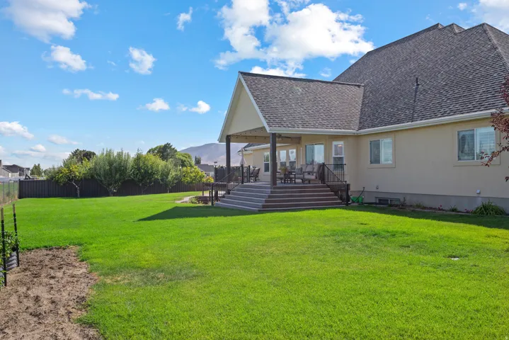 Expansive green lawn with a tiered composite deck featuring a covered patio area