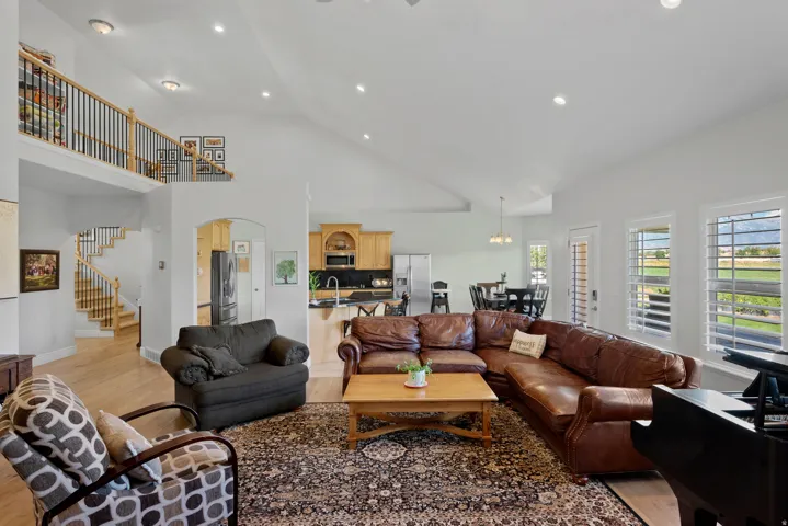 Vaulted great room featuring light wood-finish flooring, recessed lighting, and a prominent staircase with wood newel posts and black metal balusters