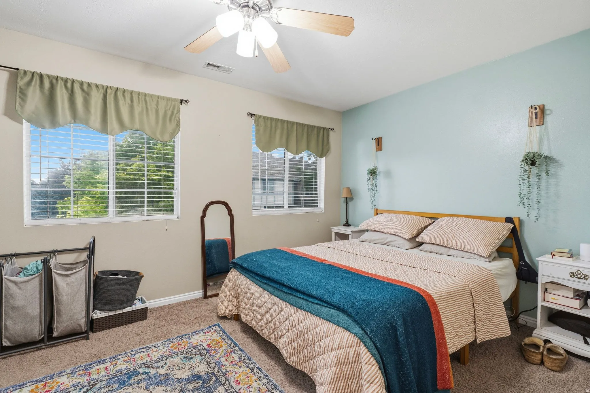 Bedroom featuring two windows with blinds, a ceiling fan, and carpet flooring
