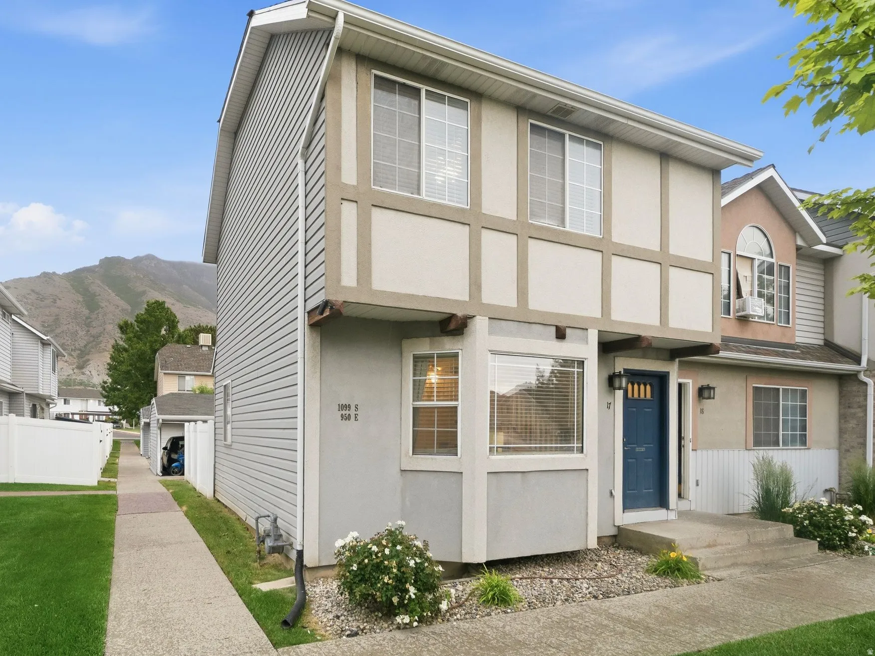 Townhome exterior featuring gray siding, a prominent blue front door with glass inserts, and a bay window on the lower level