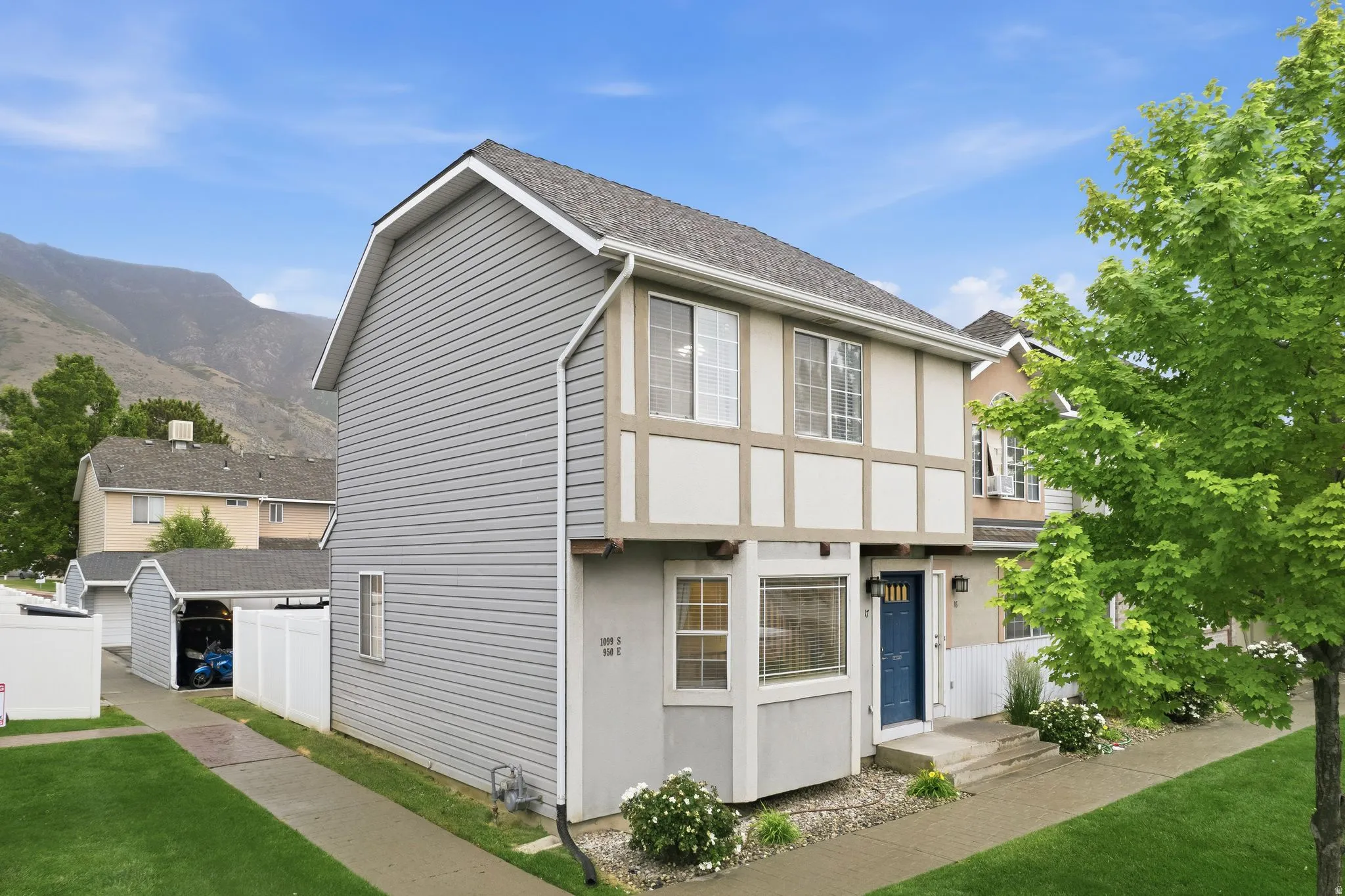 Two-story townhome with a light gray siding exterior, contrasting half-timber detailing, and a prominent blue entry door