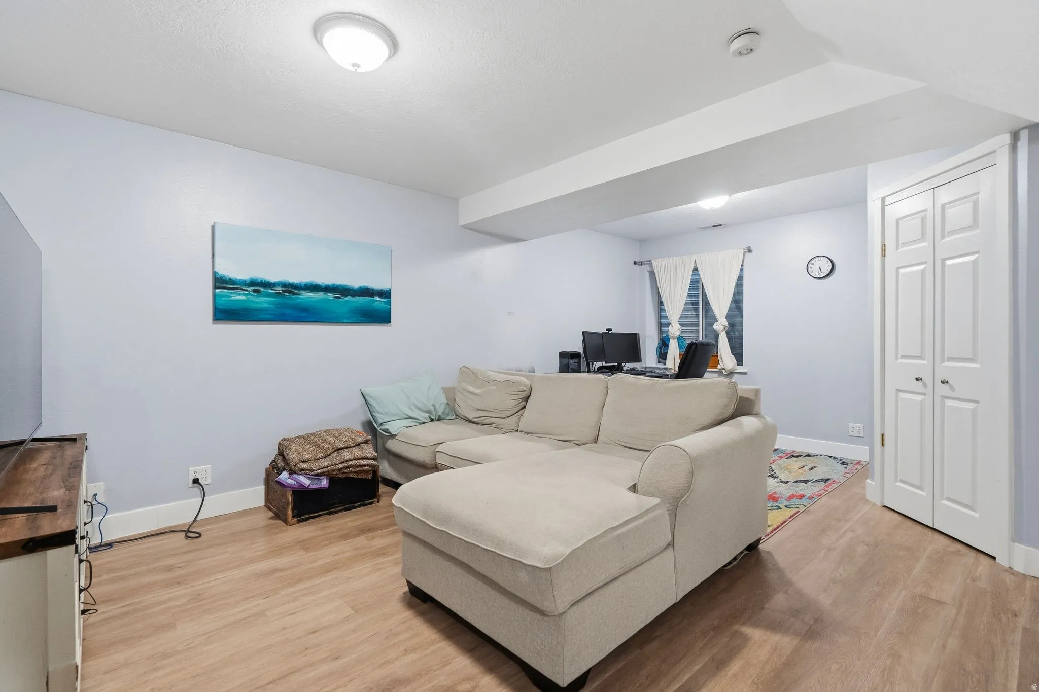 Living area featuring wood-finish flooring, light blue walls, recessed lighting, and white bi-fold closet doors
