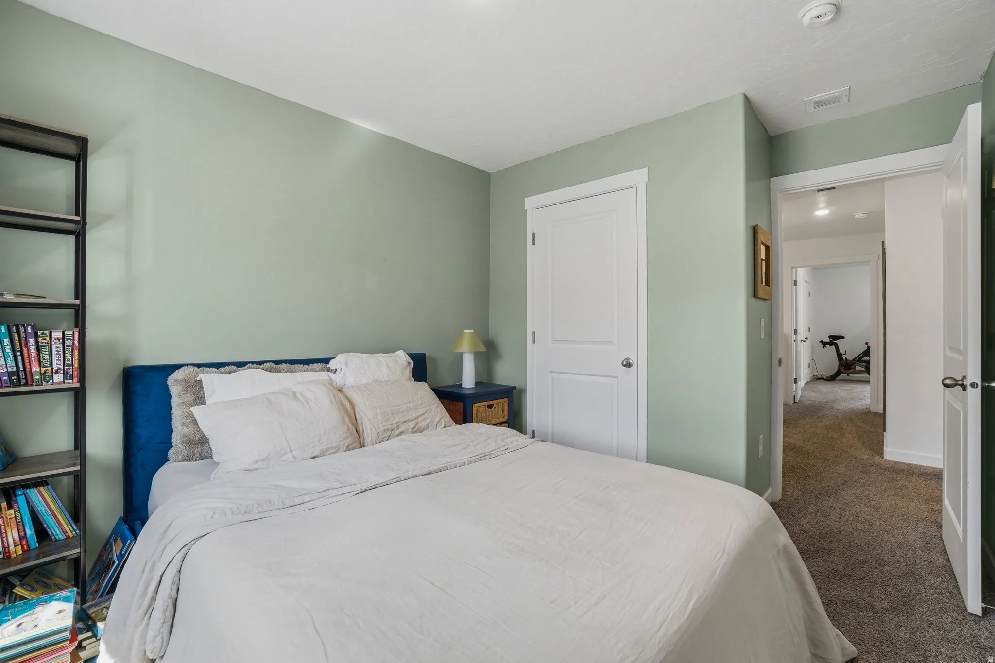 Bedroom featuring light green walls, white trim, and a white interior door