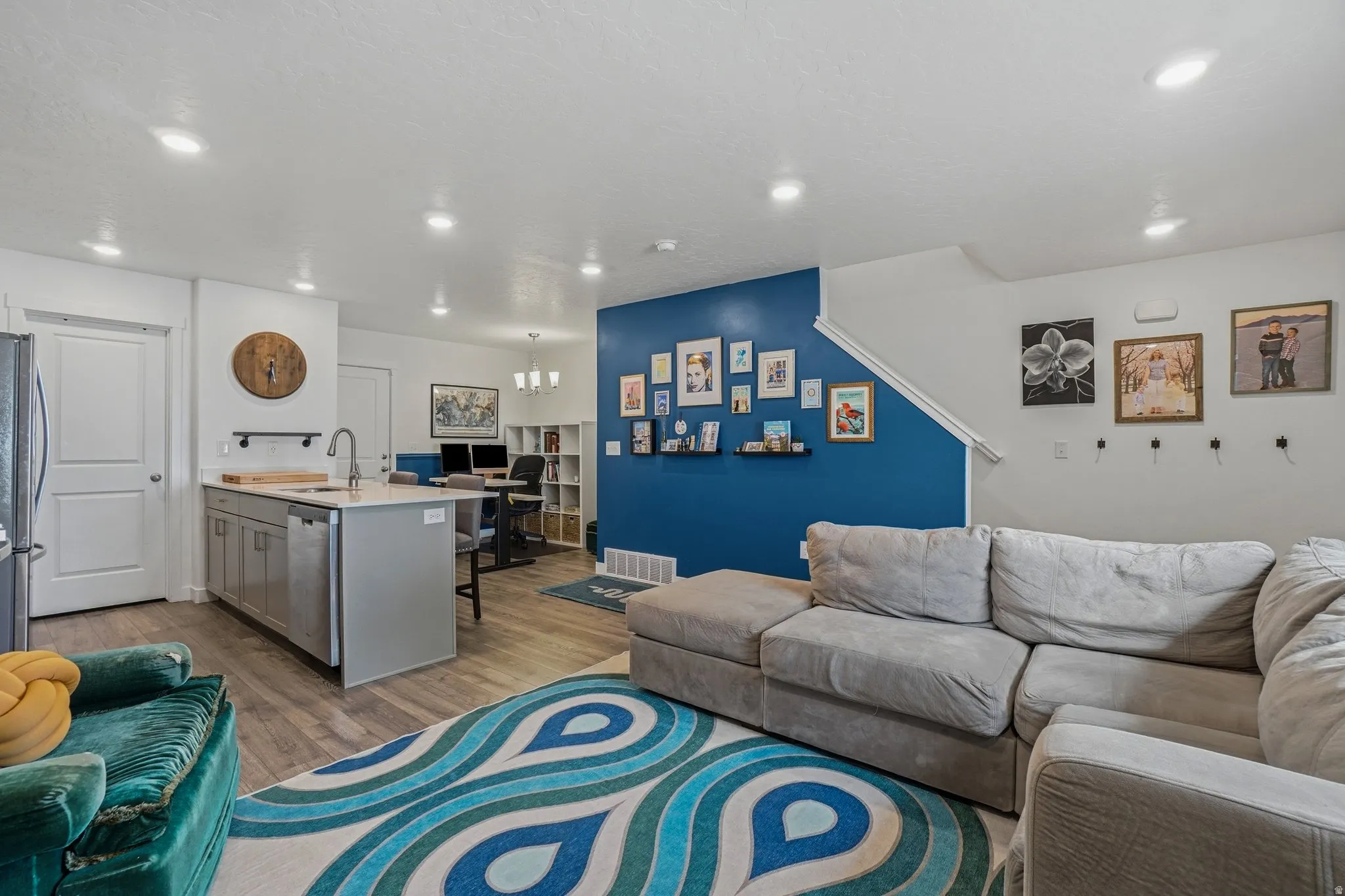 Open-concept living area featuring wood-finish flooring, recessed lighting, and a prominent accent wall