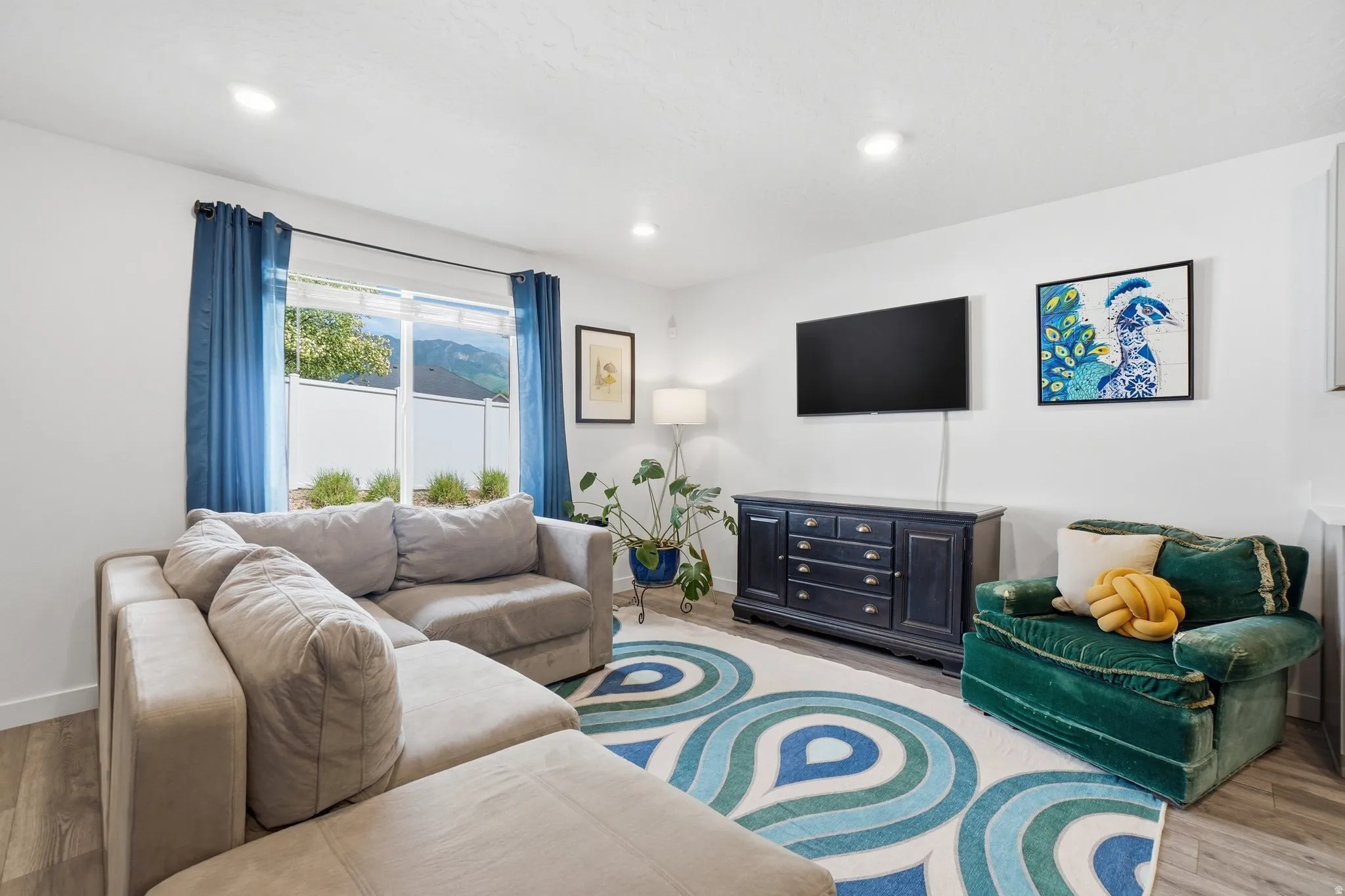 Living area featuring wood-finish flooring, recessed lighting, and a large window with a distant mountain backdrop