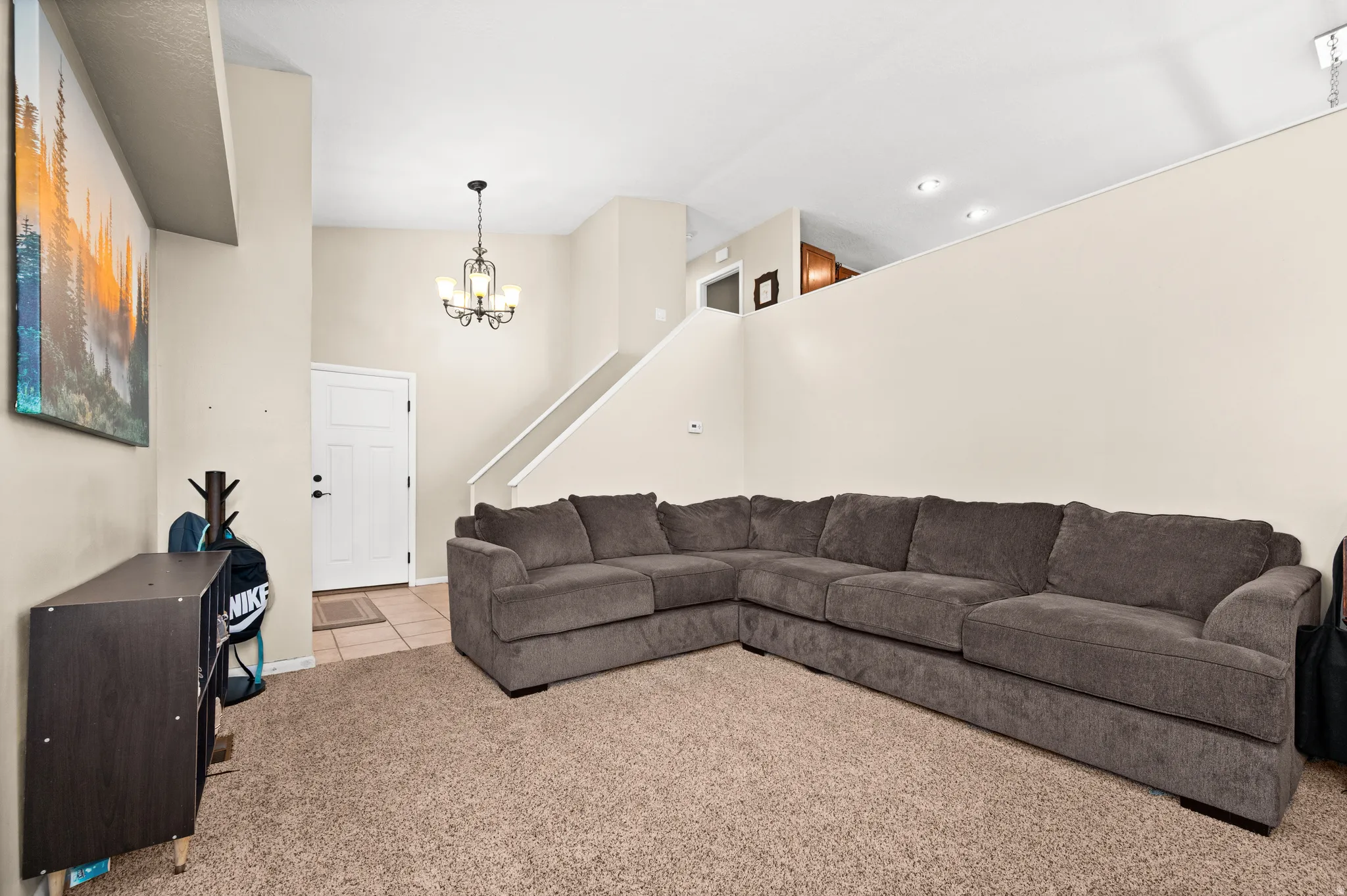 Spacious living area featuring neutral-toned walls, high ceilings, and plush carpet flooring